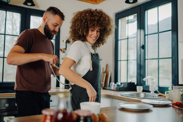 Man tying apron on woman in kitchen, preparing to cook together