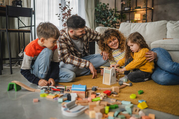 Obraz premium Parents and little children sit on floor and play with colorful toys