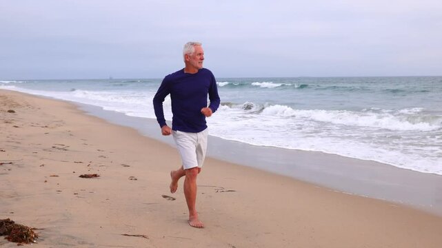 A mature 66 year old man jogging at the beach in Southern California. Slow Motion.