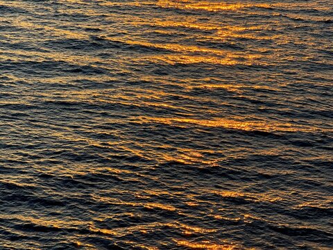 Dark blue golden ocean waves rippled surface.
