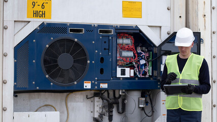 An engineer performs maintenance on a cargo refrigerator, updates the software by connecting a computer to the cold generator.