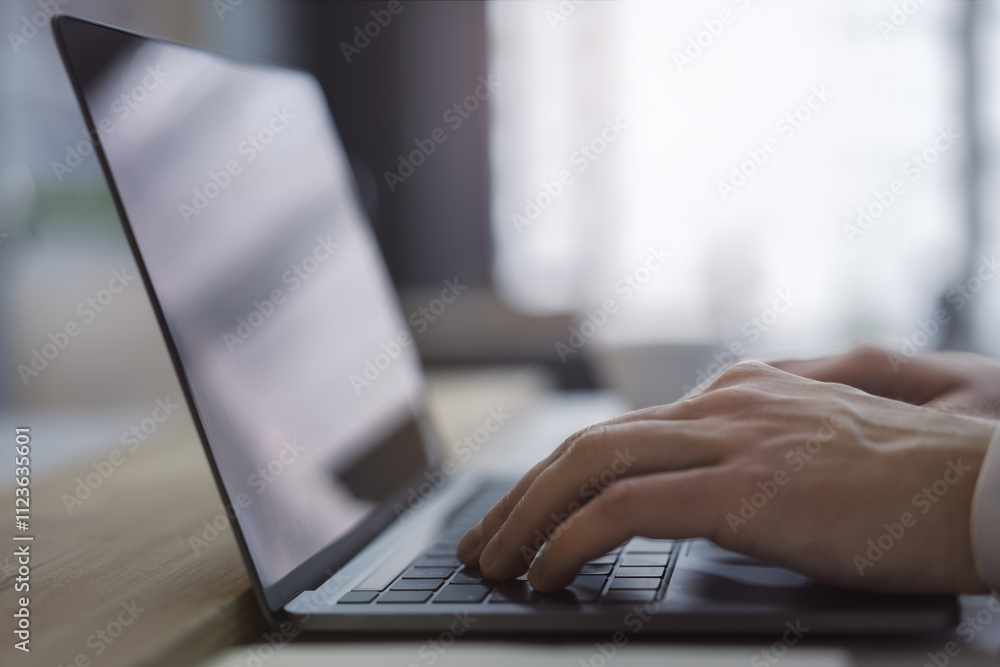 Poster with the office setting blurred in the backdrop, the image shows a close-up of a man's hands typing 