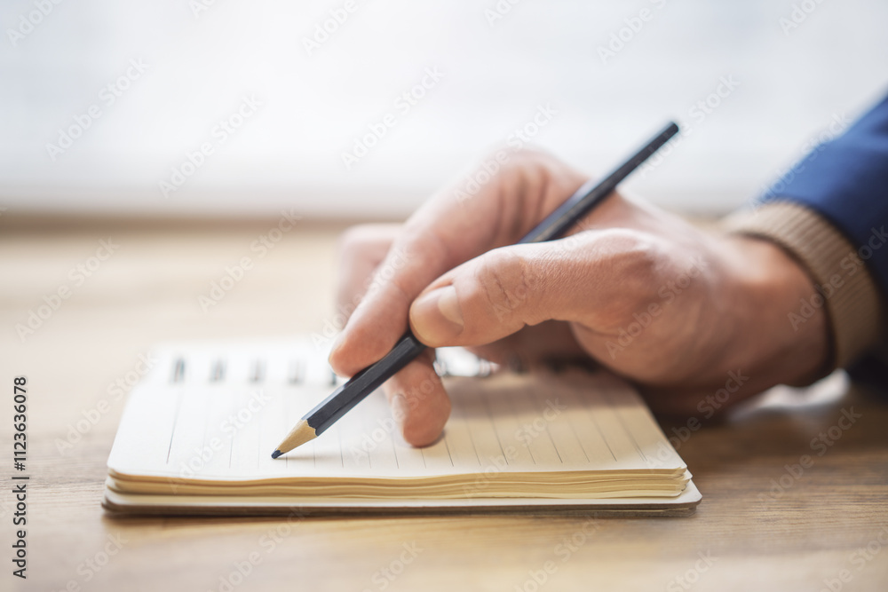 Aufkleber the image highlights a man's hand writing in a notepad, with a faintly blurred surrounding