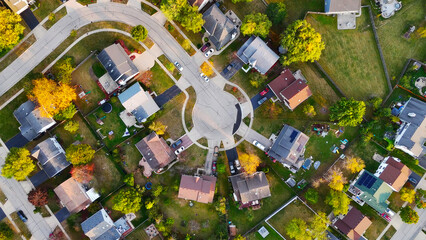 Aerial View of Suburban Cul-de-Sac Neighborhood. A top-down view of a suburban cul-de-sac neighborhood showcasing houses, lawns, driveways, and autumn trees in vibrant colors.