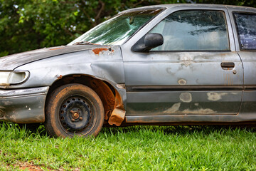 Old, weather-damaged, rusty abandoned car