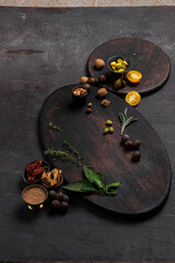 Spices and additives for dishes in bowls on a dark board on a dark table