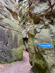 Paths between rocks in the forest in the Mullerthal region of Luxembourg, with the ground covered in dry leaves.