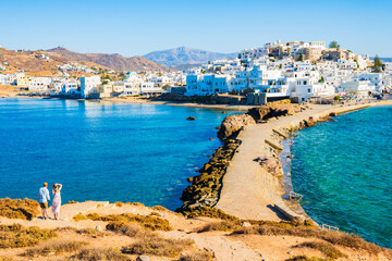 Couple of unidentified tourists looking at Naxos port and sea coast from Portara hill, Naxos...