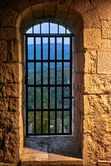 An old window with an iron grill and stone frame