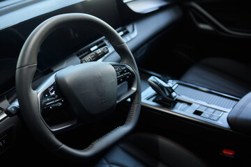 Fototapeta premium Closeup of a modern car steering wheel with control buttons for technology and convenience