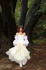 Young woman in white dress standing in the forest