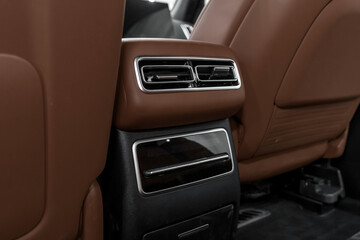 Obraz premium Deflectors for rear passengers. Luxurious modern brown leather car interior, climate control, air ducts on the car panel.
