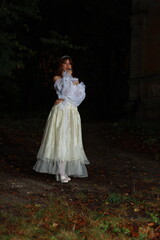 Fototapeta premium Beautiful young woman in white vintage dress in a dark forest full length