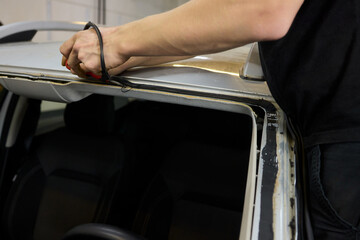 Obraz premium Automobile special workers remove old windscreen or windshield of a car in auto service station garage. Background