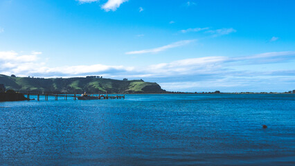 Naklejka premium Beautiful ocean sea scenes clear day calm water blue sky Otago peninsula Dunedin New Zealand boats jetty dingy 