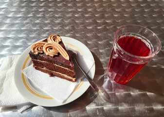 A glass of mors and a piece of cake on a plate on the table in a cafe. © Sofya