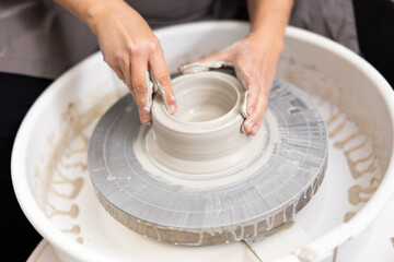 Fototapeta premium skilled hands of master on potter's wheel create future craft tableware