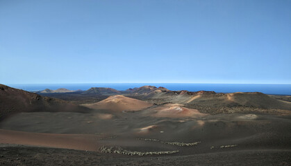 Volcanic landscape in the Timanfaya National Park on Lanzarote Spain Europe with a view over various hills and sea in the background