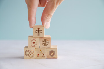 Hand holding wooden block with Ethical icons, business ethics and corporate compliance concept