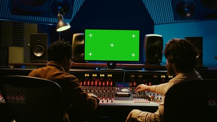 Diverse producers mixing and mastering tracks with mockup display on computer, recording before...
