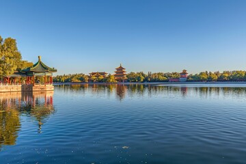 Fototapeta premium Calm lake reflecting pagodas under a clear blue sky.