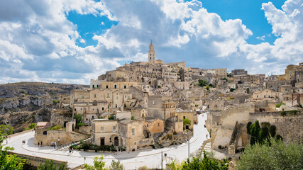 Obraz premium Nestled in the hills of Puglia Italy, Matera boasts ancient stone houses and winding streets, bathed in golden sunlight. A stunning blend of history and scenic beauty creates an enchanting atmosphere.