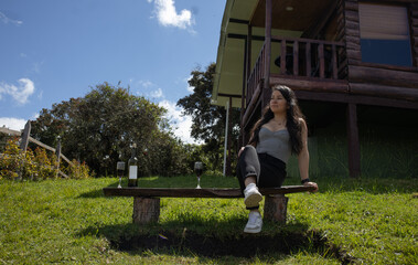 Fototapeta premium Woman sitting on a bench outdoors near a rustic wooden cabin