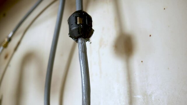 Leaky old faucet hose under kitchen sink leaking water