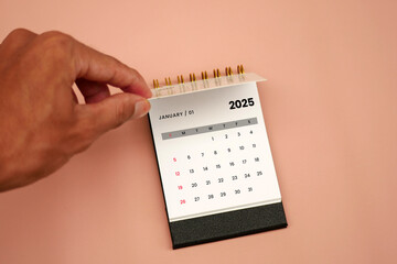 Businessman's hand turns the calendar page from December 2024 to January 2025. Business planning...