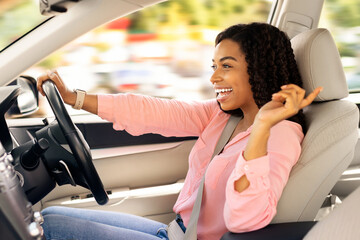 Road Trip Concept. Profile side view portrait of excited playful black woman driving luxury car,...