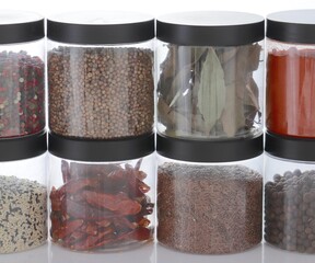 Transparent containers placed in a row above each other with various types of spices close-up. White background.