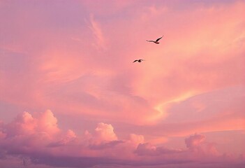Fototapeta premium Fantasy sky at sunset with vibrant cotton candy pink pastel clouds swirling in a lavender background, silhouetted birds flying in the distance