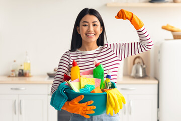 Happy asian lady with cleaning tools showing muscle strength, wearing rubber gloves, young woman...