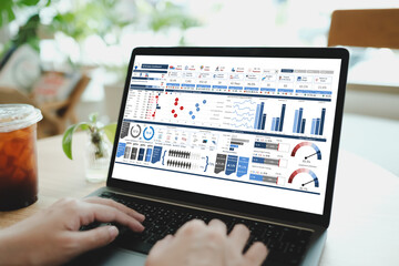 A person analyzing data on a laptop screen displaying a detailed HR and sales dashboard in a modern...