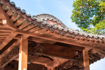 Close-up view of a traditional Chinese pavilion roof featuring intricate wooden latticework, curved eaves adorned with ceramic tiles, and a decorative ridge