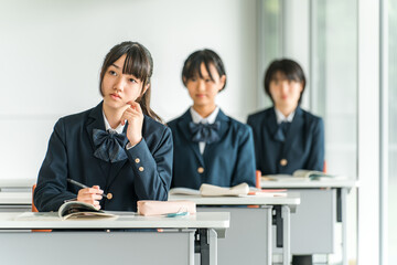 Obraz premium 学校の教室で真剣に授業を聞く制服姿の小学生・中学生・高校生・女子高生（友達） 