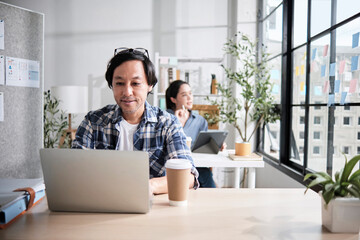 Two Asian startup partners, male Japanese worker concentrates working in a casual small business...