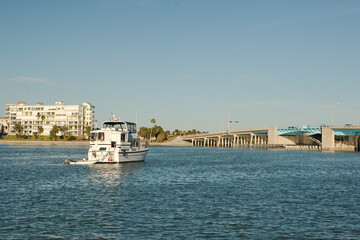 View from over intercoastal  towards large white Boats in the middle of water near Corey Causeway Drawbridge. Towards far shore and condos. Puffy white and gray clouds. Late afternoon sun near sunset
