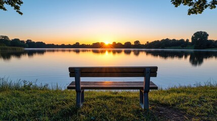 A serene view of a lake at sunrise with a wooden bench overlooking the calm water.
