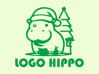 Fototapeta premium Green hippo with hat beside mini Christmas tree, perfect for holiday greeting cards, festive designs, childrens illustrations, and seasonal graphics