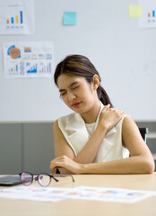 Young asian businesswoman grab the shoulder with her hand. To relieve pain from working overtime for long periods of time.