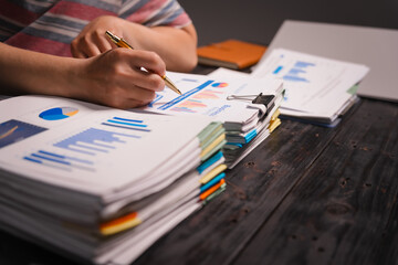 A man working late at home sits at his desk analyzing financial charts, checking stock market data...