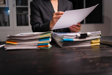 A young Asian man in a formal suit works late at night at his desk, analyzing stock market charts...