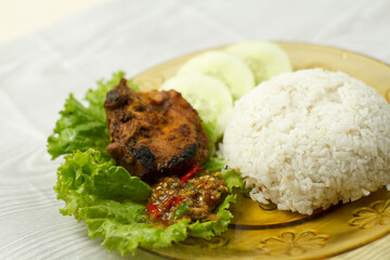 Ayam Bakar, Indonesian roasted chicken served with rice, fresh vegetable, and sambal. A flavorful traditional dish, perfect for showcasing authentic Indonesian cuisine in restaurants.