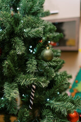 Green sparkling ball hangs on a Christmas tree branch with glowing garlands