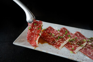 Wagyu Australia, a delicious beef with very high marbling served on white plate with sauce and shopped scallion.