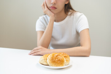 Gluten allergy, asian young woman, girl refusing to eat, looking at bread slice on plate in...