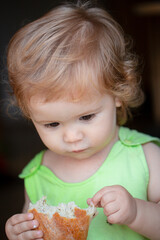 Naklejka premium Little boy eating rusk with rusk with raisins. Baby eating bun bread. Close up face. Cute toddler child eating sandwich, self feeding concept.