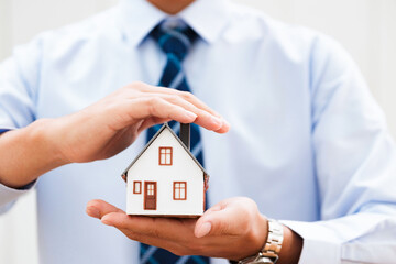 Real Estate Agent Protecting House Model in Hand