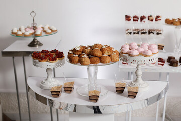 exquisite dessert table setting. In the foreground are three stands with various desserts. On the left is a stand with tartlets decorated with fresh raspberries.
